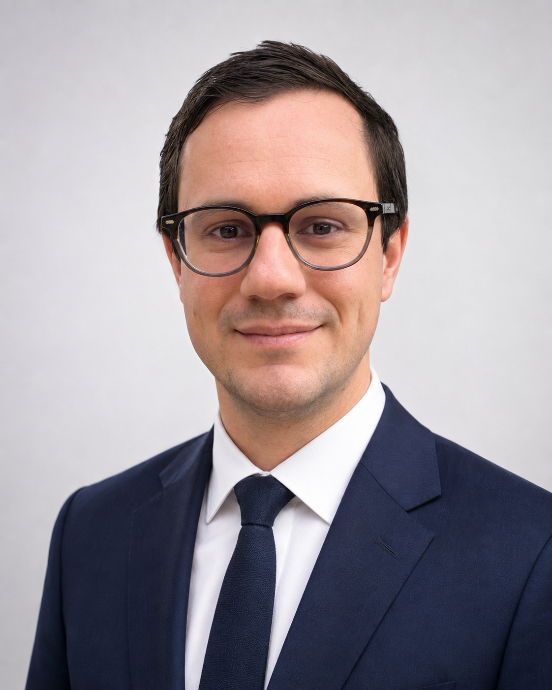 Dr Michael Rowe, Consultant Clinical Oncologist, wearing glasses and a navy suit